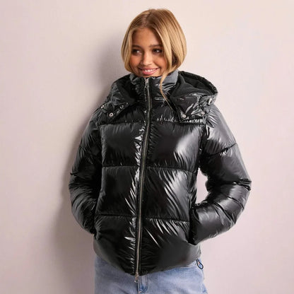 Doudoune brillante femme noire à capuche, coupe courte, portée devant un mur clair